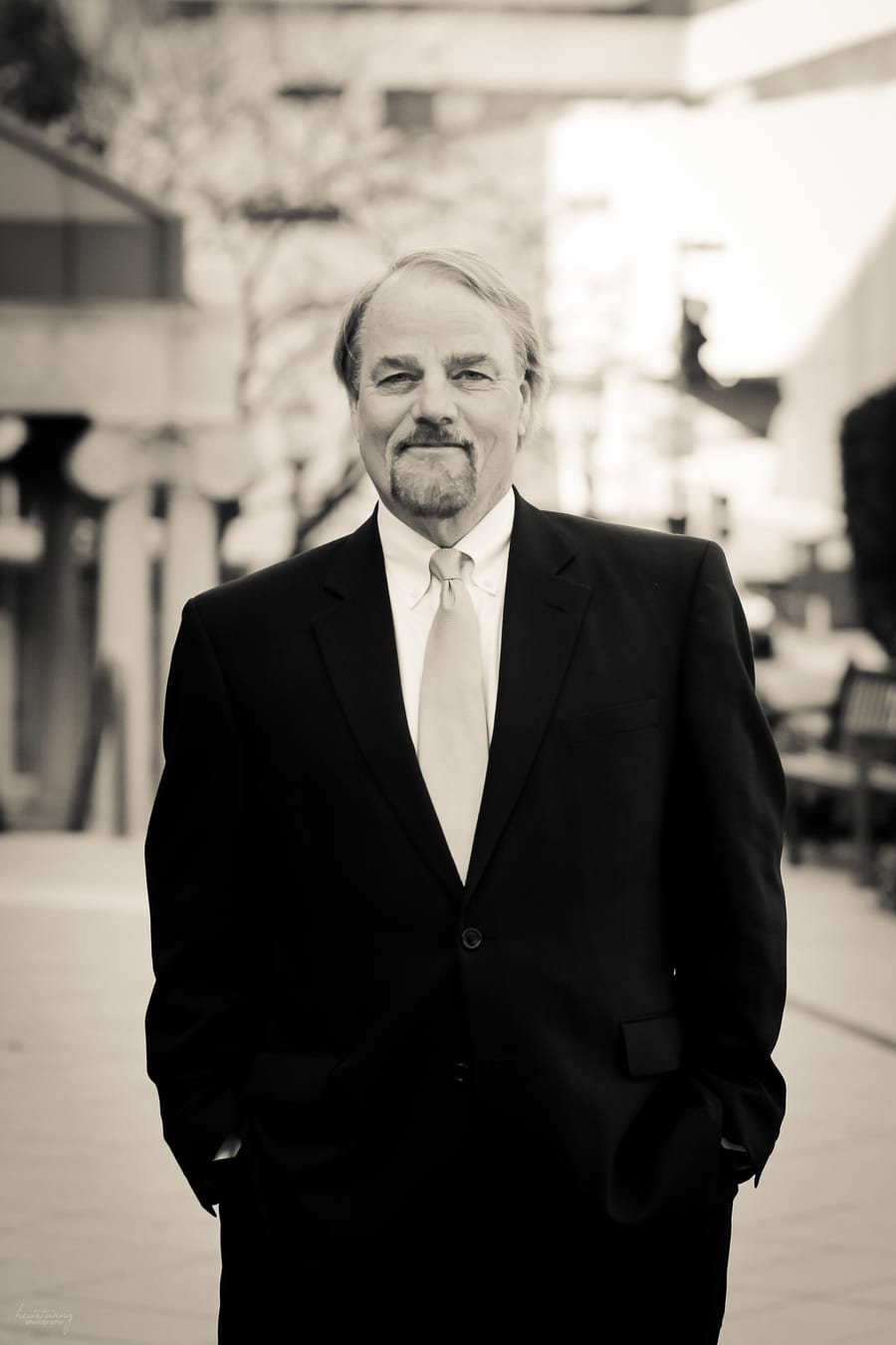 A man in suit and tie standing on sidewalk.